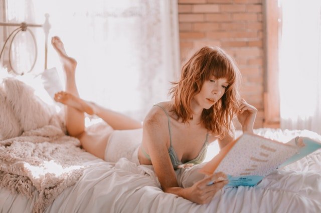 Žena ležiaca v posteli, ktorá číta časopis.jpg